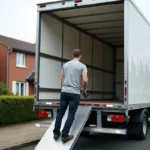 Homme en train d'utiliser le hayon hydraulique d'un camion de déménagement 20m3 devant une maison en banlieue