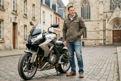 Homme debout à côté d'une moto moderne sur une rue pavée de Poitiers avec des bâtiments historiques en arrière-plan