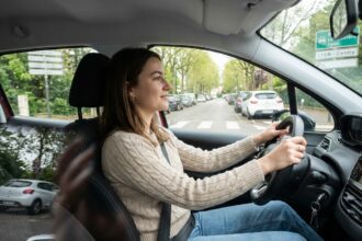 Jeune femme au volant d'une voiture en ville Rhône