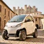 Voiture sans permis blanche garée sur les pavés d'Avignon avec le Palais des Papes en arrière-plan